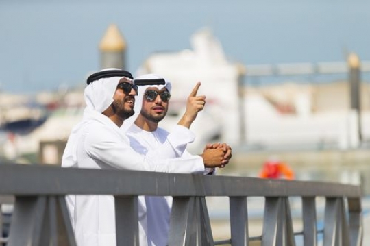 Arab men leaning on the rail talking to each other|