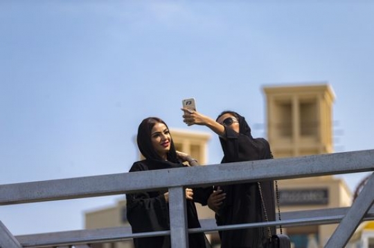Arab women standing by the dock taking a photograph together|