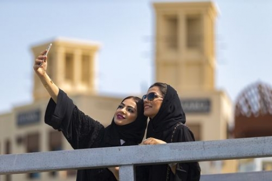 Arab women dressed in the traditional UAE attire standing by the dock taking a picture together|