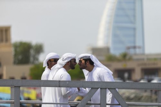Arab men standing by the dock saying hello to each other|