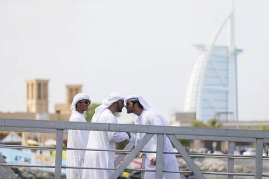 Arab men standing by the dock talking to each other with a background of the famous Burj Al Arab|