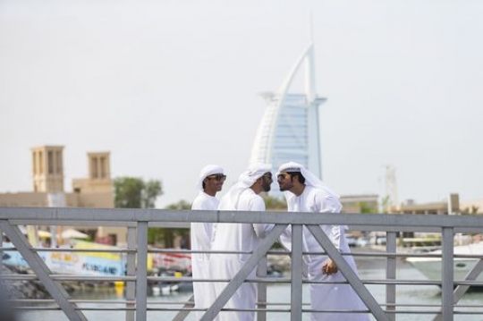 Men dressed in the traditional UAE attire greeting each other |