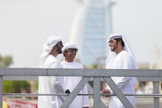 Three arab men standing by the dock talking to each other|
