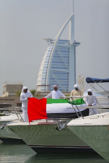 Middle eastern men attaching the UAE flag to the yacht to celebrate National Day|