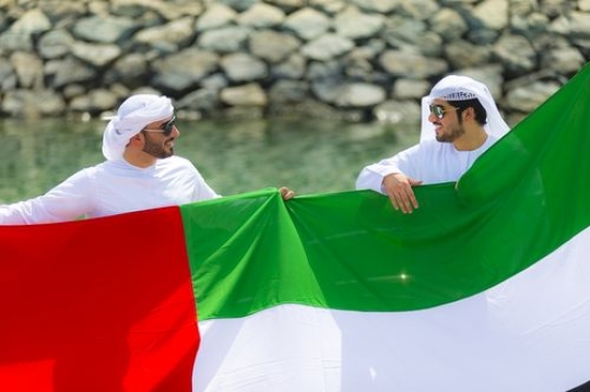 Two arab men holding the UAE Flag during the celebrations of National Day|