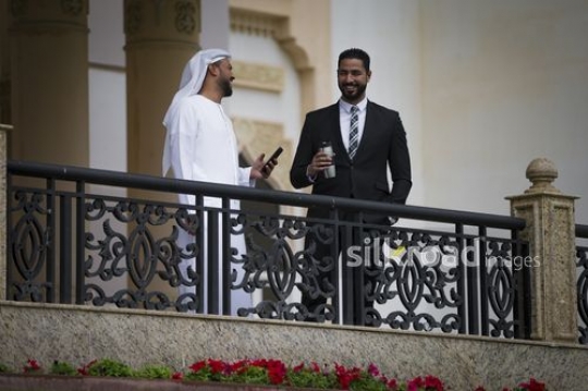 Middle Eastern men standing on the bridge laughing together|-