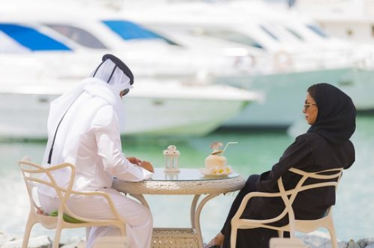 Arab man and woman sitting outside and talking to each other|