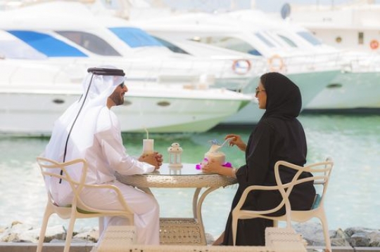 Two arab people sitting and talking to each other while having cold drinks|