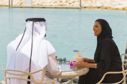 Arab woman and man are sitting outside and talking to each other|