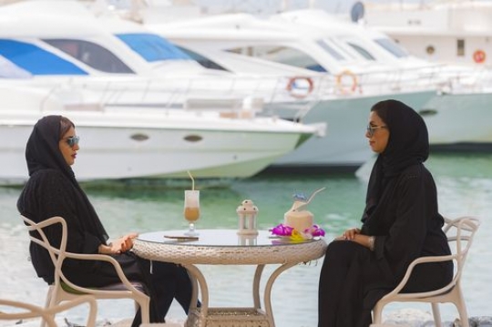 Two female friends sitting and talking to each other over coffee|