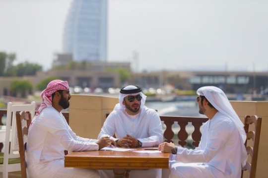 Business men dressed in the traditional UAE attire during a meeting|