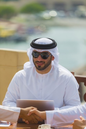 Arab man during a meeting while two men are shaking hands|