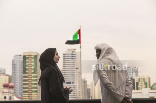 Middle Eastern man and woman standing talking to each other|-