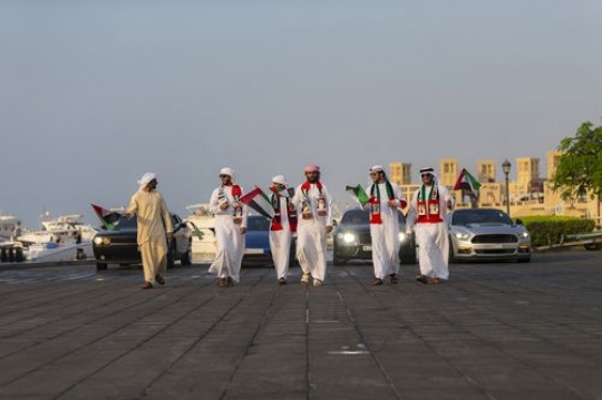 Middle Eastern men followed by Luxury cars celebrating National Day|-