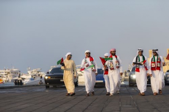 Emirati men in motion during a National Day Parade followed by Luxury cars|-