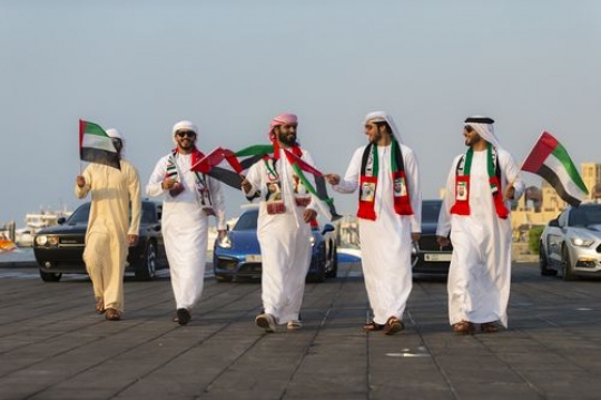 Middle eastern men dressed in the UAE traditional attire representing their country during a national day parade|-