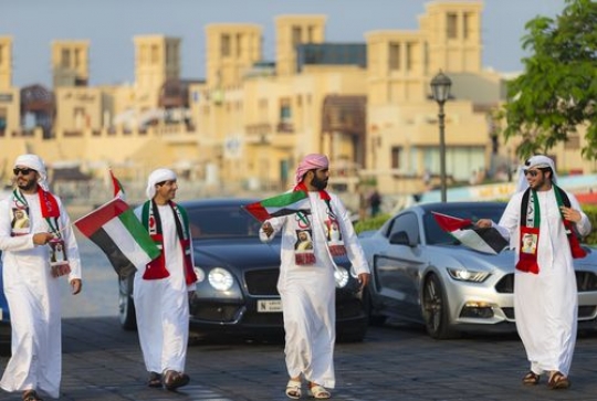 Arab men and luxury cars in motion during the UAE national Day|-
