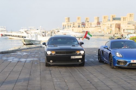 Arab men driving their cars during a national day parade|-