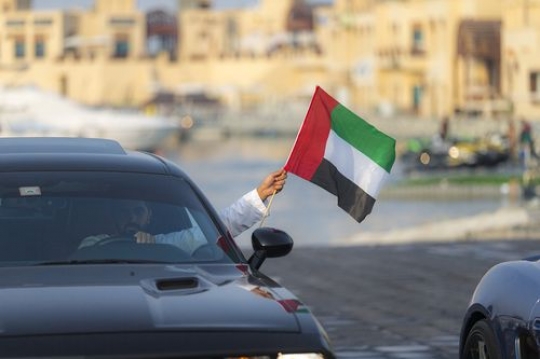 Middle eastern man celebrating his country while driving a black car|-