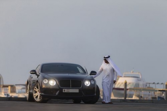 Arab man closing the door of his black vehicle|-