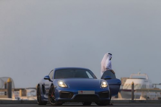 Arab man exiting his blue luxury vehicle|-