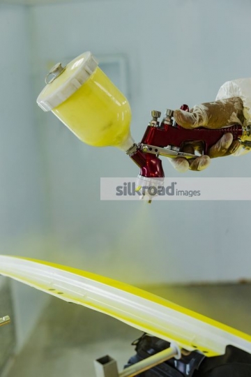 Engineer spray painting the part of the car|