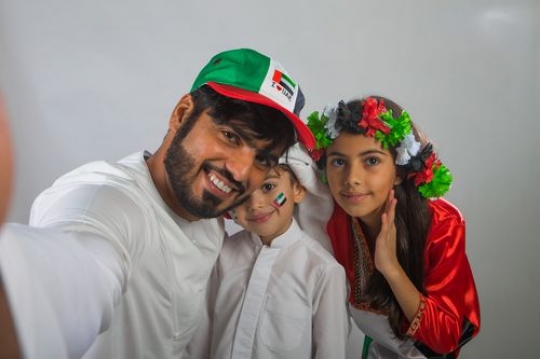 Middle Eastern man taking a selfie with the kids for National Day