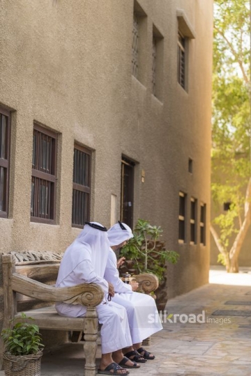 Arab grandfather and father sitting on the bench together|-
