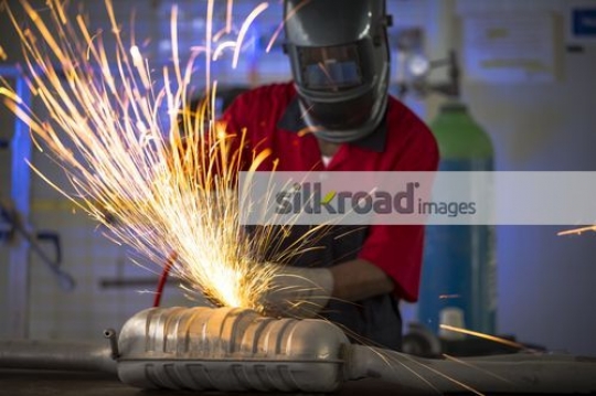 Mechanic using machine to cut the metal part for the car|