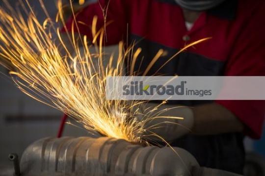 Mechanic using machine to cut the metal for the car|