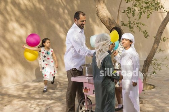 Middle Eastern kids getting sweets from the Middle Eastern man|-