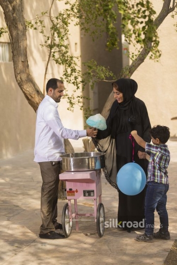 Middle Eastern man offering cotton candy to the mother|-