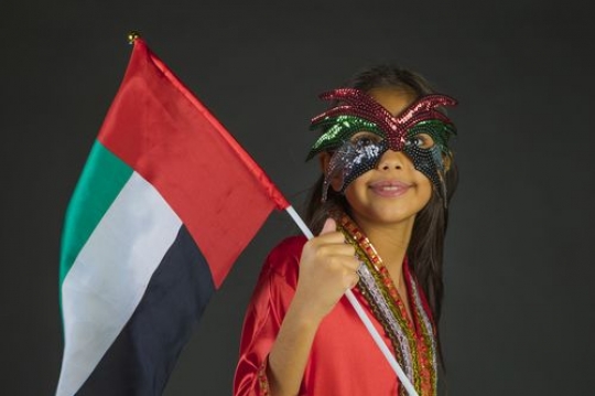 Girl carrying the UAE flag celebrating National Day