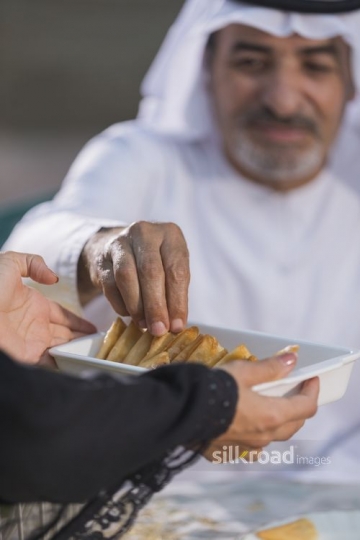 Arab man taking food of the plate offered by the woman|-