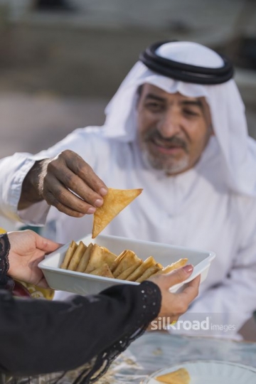 A close up of an arab man filling up his plate|-