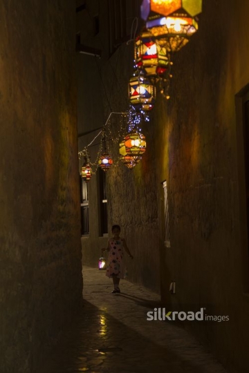 Arab girl running through the pathway decorated by Ramadan Lanterns|-