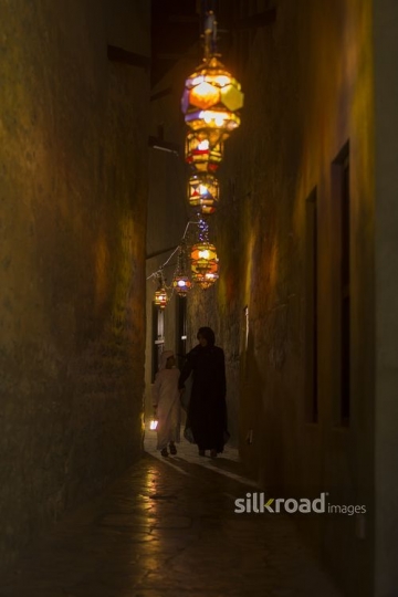 Arab boy carrying a Ramadan Lantern walking next to his mother|-