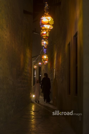 Arab boy carrying a Ramadan Lantern while walking next to his mother|-