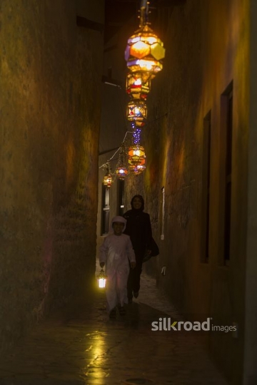 Arab mother and son walking through the pathway decorated by Ramadan Lanterns|-