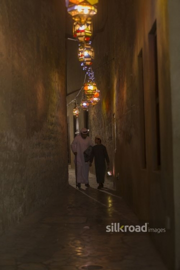 Arab father talking to his son while walking through the pathway decorated by Ramadan Lanterns|-
