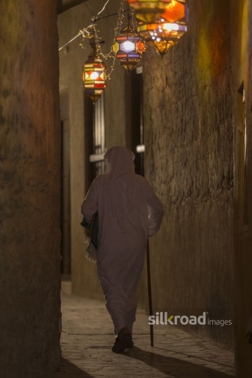 Arab man walking through the alleyway decorated by Ramadan Lanterns|-
