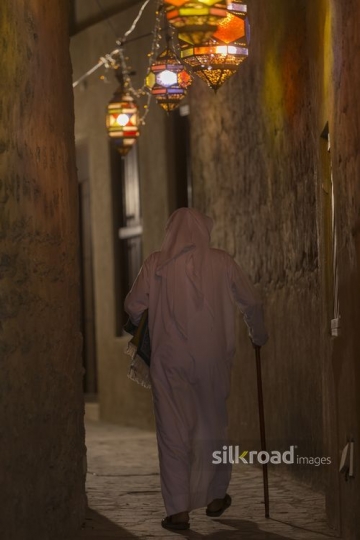 Middle Eastern man dressed in a traditional attire carrying a prayer rug during Ramadan