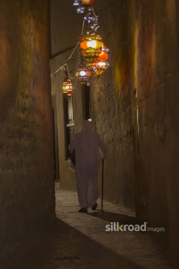 Arab man walking through the pathway decorated by Ramadan lanterns