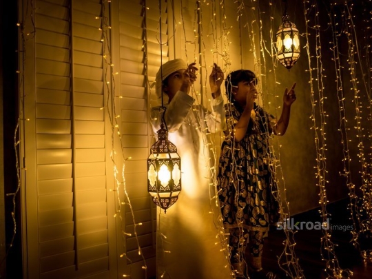 Brother and sister playing with ramadan lights|-