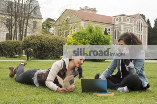 University students sitting on the grass talking|