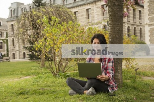 Student sitting on the grass using the laptop |