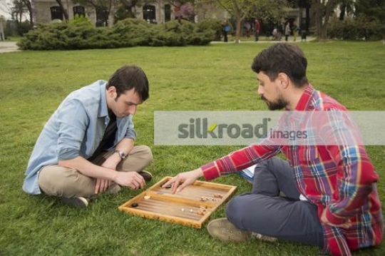 Friends sitting on the grass playing a game|