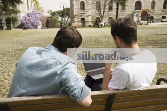 Men sitting on the bench together studying