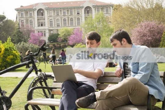 Students sitting on the bench using laptop