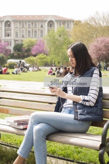 Student using her mobile sitting on the bench|